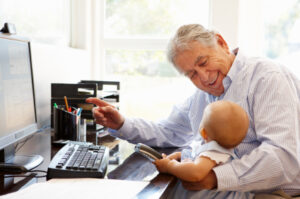 Senior Hispanic man with computer and baby Small business help for business goals
